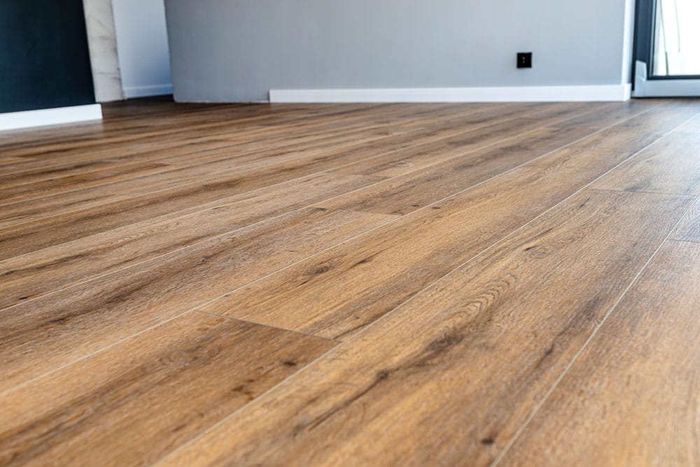 Modern vinyl panels imitating wood in the living room with selective focus and a shadow falling from the window. Houten vloeren Lisse